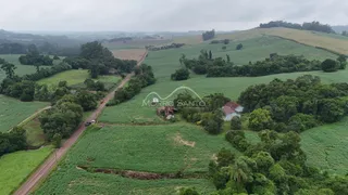 Vista aérea de uma propriedade rural com campos verdes e colinas.
