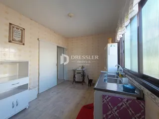 Interior de uma sala com paredes claras e piso de madeira clara.