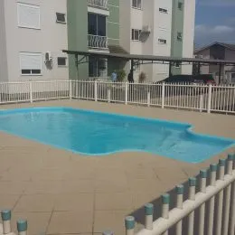 Foto de uma piscina externa com muro branco em uma propriedade.