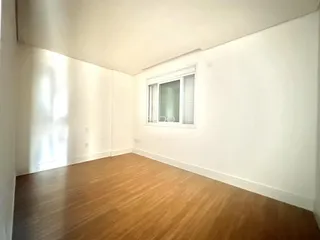 Foto de uma sala interna com piso de madeira clara e paredes brancas.