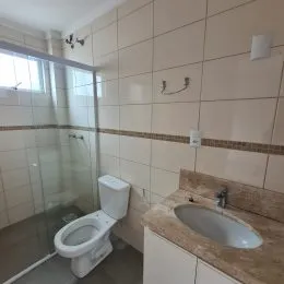 Foto de um banheiro com revestimento de azulejos claros e vaso sanitário.