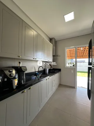 Cozinha moderna com armários brancos e bancadas escuras.