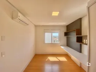 Ambiente interno de uma sala com piso de madeira e janela.