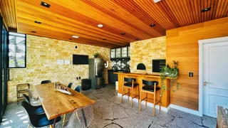 Ambiente interno de uma sala de estar com piso de pedra e forro de madeira.