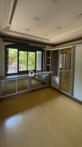 Sala de estar com piso de madeira clara e grandes janelas.