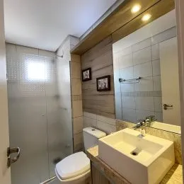 Foto de um banheiro com revestimento de azulejos brancos e louças sanitárias.