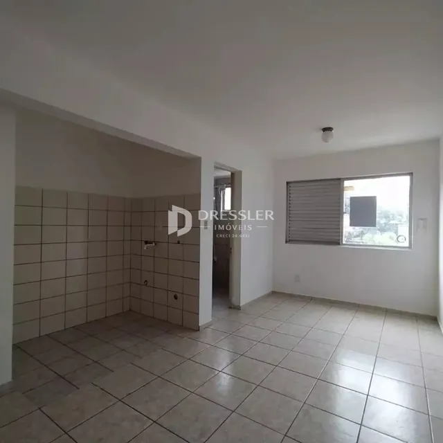 Interior de uma sala com piso de cerâmica clara e paredes brancas.