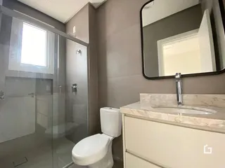 Banheiro com box de vidro e bancada de mármore claro.