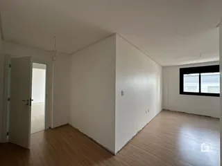 Vista interna de um ambiente com paredes brancas e piso de madeira.