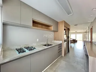 Vista da cozinha moderna com armários cinzas e bancadas claras.