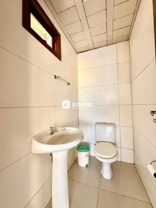 Banheiro com pia e vaso sanitário em revestimento branco.