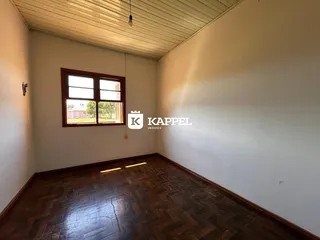 Foto de um cômodo com piso de madeira e janela em uma residência.