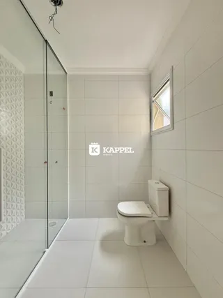 Foto interna de um banheiro com revestimento branco e piso claro.