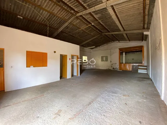 Interior de um espaço amplo com teto de zinco exposto e paredes brancas.