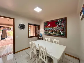 Ambiente de jantar com mesa branca e cadeiras em uma sala de estar.