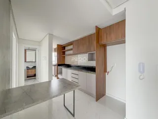 Vista interna de uma cozinha moderna com armários de madeira e piso de porcelanato claro.
