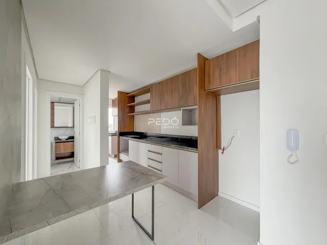 Vista interna de uma cozinha moderna com armários de madeira e piso de porcelanato claro.