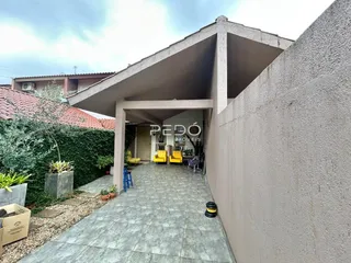 Vista externa de uma propriedade com um pátio coberto e jardim.