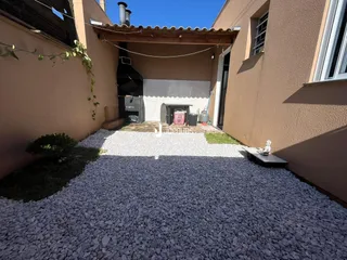 Vista externa de um pátio com área de cascalho entre duas edificações.