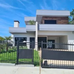 Fachada de uma residência moderna branca com cerca preta em Lajeado.