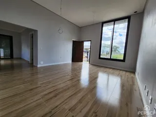 Sala de estar ampla com piso de madeira clara e grande janela.