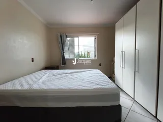 Quarto com cama e armário branco na sala.