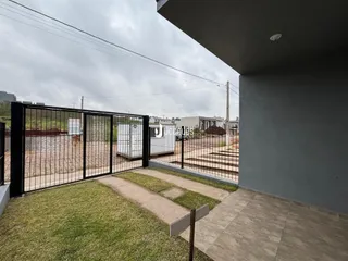 Vista da fachada de uma propriedade com portão de ferro e área gramada.