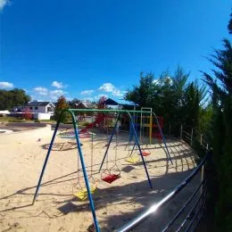 Foto de uma área externa com areia e estruturas de playground em um quintal.