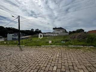 Vista externa de uma propriedade com área pavimentada e vegetação ao redor.