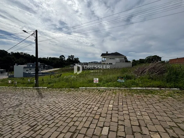 Vista externa de uma propriedade com área pavimentada e vegetação ao redor.
