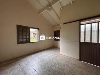 Foto de um cômodo interno com piso de cerâmica e teto de vigas expostas.