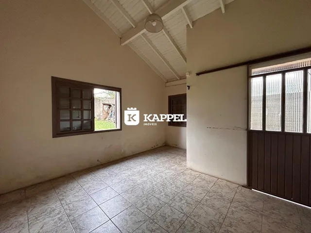 Foto de um cômodo interno com piso de cerâmica e teto de vigas expostas.