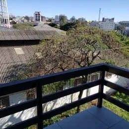 Vista de uma varanda com vegetação e grade de proteção.