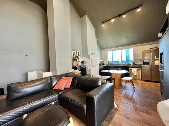 Sala de estar com sofá de couro marrom e piso de madeira.