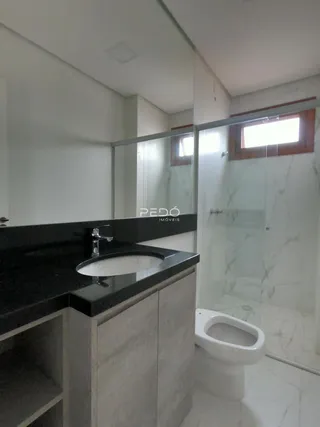 Banheiro moderno com box de vidro e bancada escura.