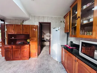 Interior da cozinha com armários de madeira e piso cerâmico.