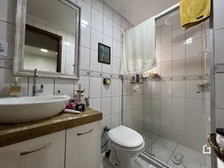 Foto de um banheiro com azulejos brancos e box de vidro.