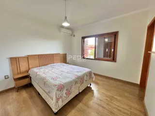 Quarto com cabeceira de madeira e janela em um imóvel no Brasil.