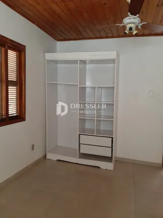 Um armário branco de parede está instalado em um cômodo com teto de madeira.