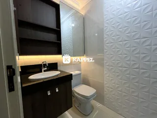 Foto de um banheiro com bancada escura e revestimento branco.