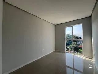 Interior de uma sala com paredes brancas e grande janela com vista para a paisagem.