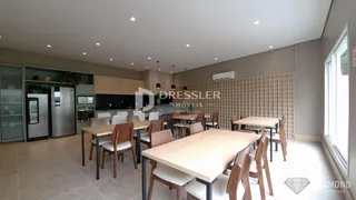 Vista de uma sala de jantar com mesa de madeira e cozinha moderna.