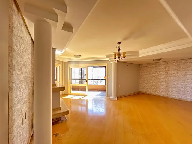 Vista interna de um ambiente amplo com piso de madeira clara.