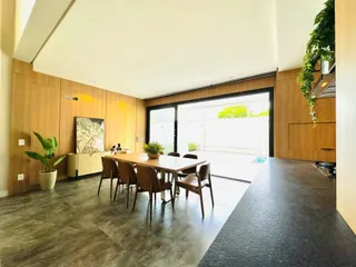 Sala de jantar ampla com mesa de madeira e portas de vidro que dão acesso ao exterior.