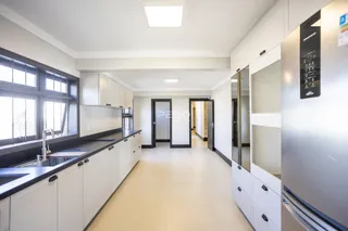 Vista da cozinha moderna com armários brancos e bancadas escuras.