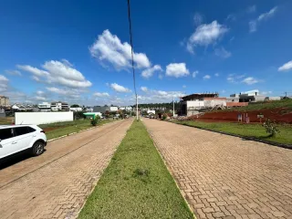 Vista externa da propriedade mostrando uma rua pavimentada e uma faixa de gramado sob um céu azul.
