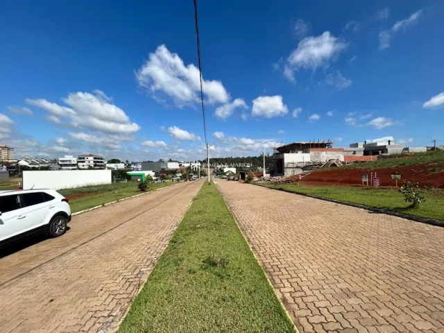 Vista externa da propriedade mostrando uma rua pavimentada e uma faixa de gramado sob um céu azul.