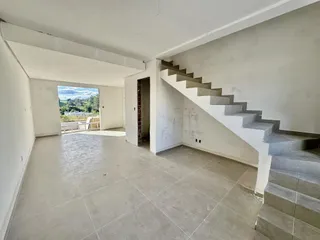 Ambiente interno amplo com piso de concreto e escadaria em uma residência.
