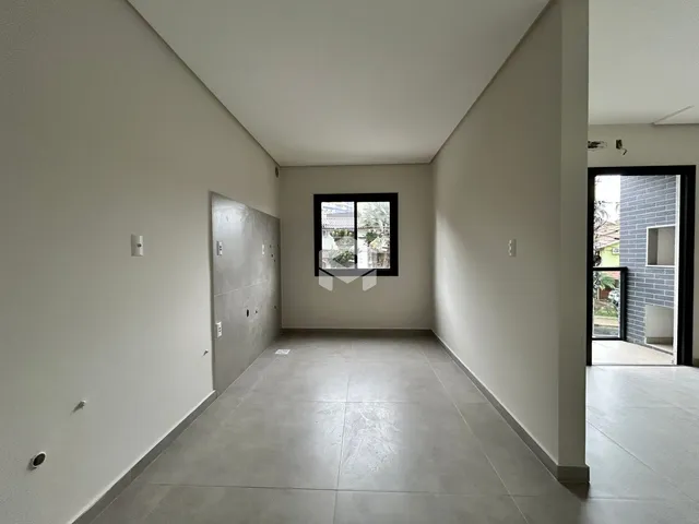 Vista interna de um ambiente com paredes brancas e piso cinza.