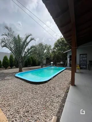Foto de uma piscina externa cercada por cascalho e vegetação.